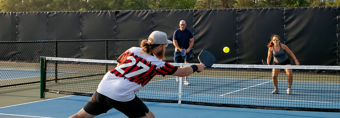Three people playing pickleball